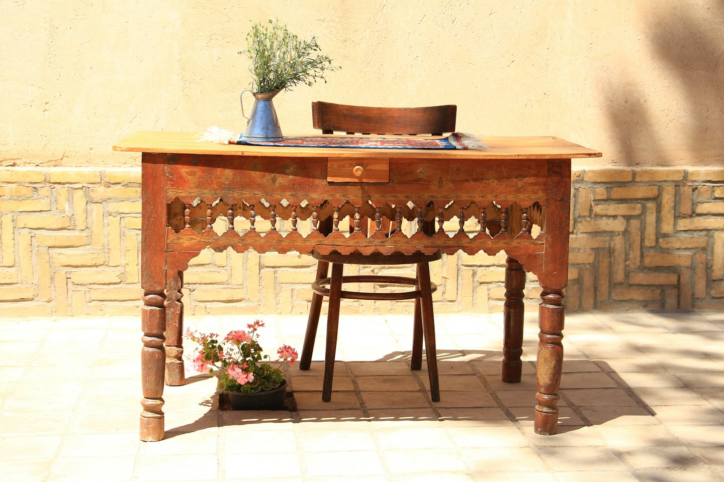 A carved wooden table and chair set sit outdoors.
